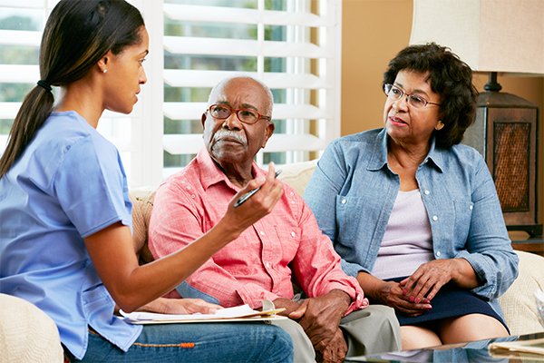 Home nurse making notes during home visit with senior couple